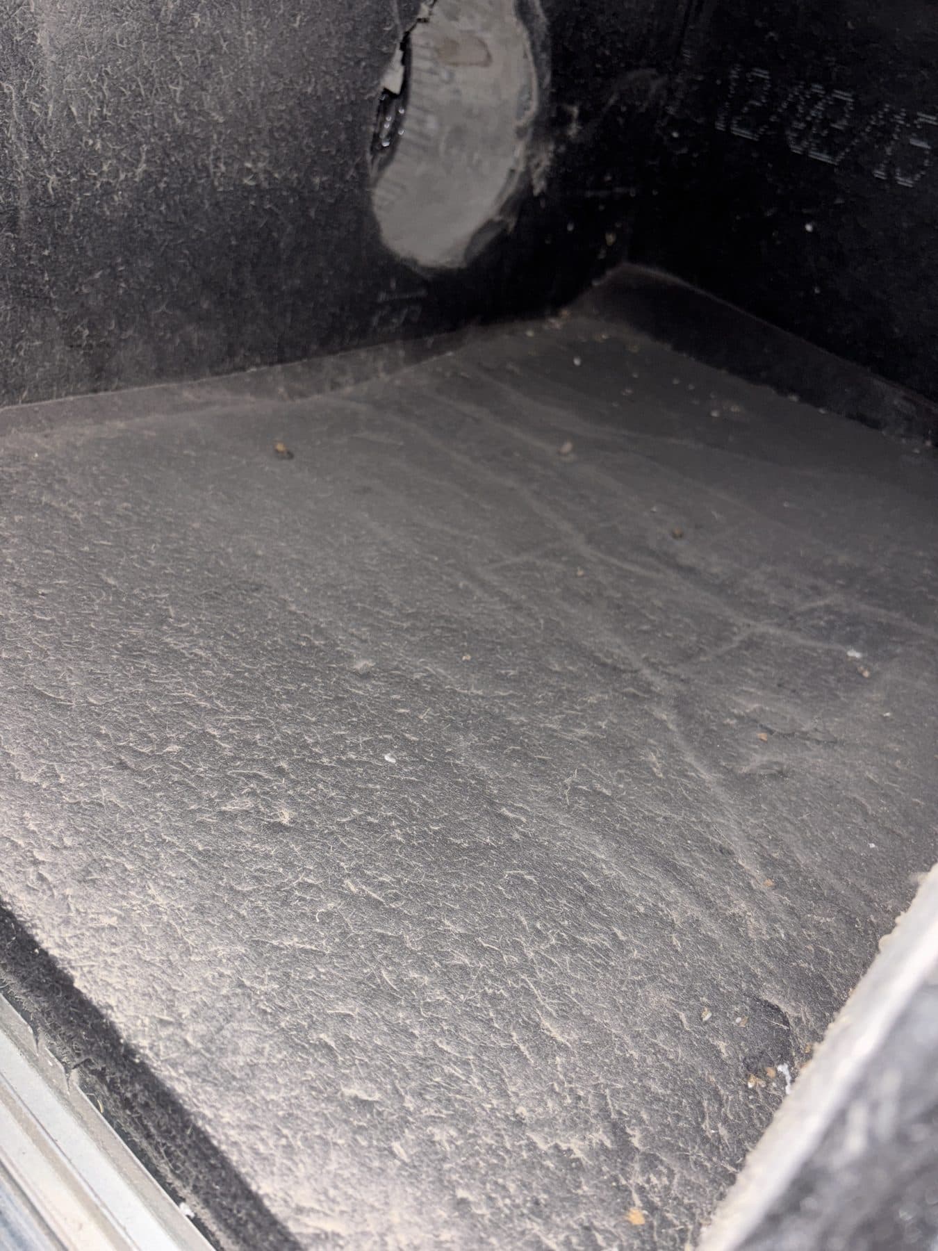 Interior of a return plenum box showing dust settled across the surfaces